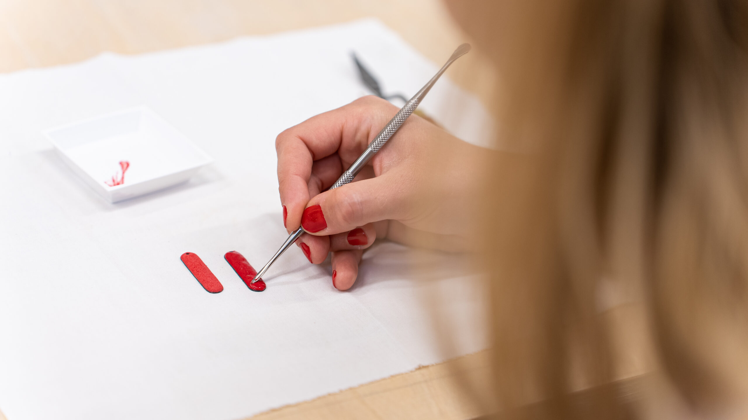 Clémence dépose une couche d'émail rouge intense